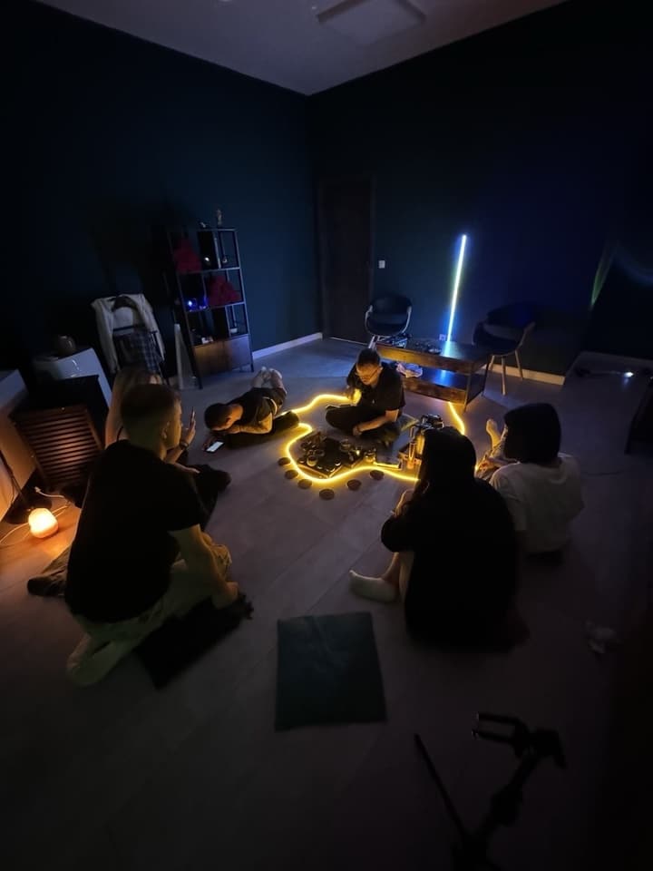 A group tea ceremony: guests sitting in a circle on the floor around a lit tea tray